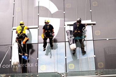 Paris, Fransa - 3 Temmuz 2020: Modern bir binanın cam duvarında çalışan üç adam