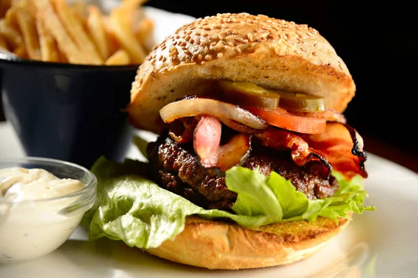 Patates kızartmalı hamburger ve siyah arkaplanda sos.