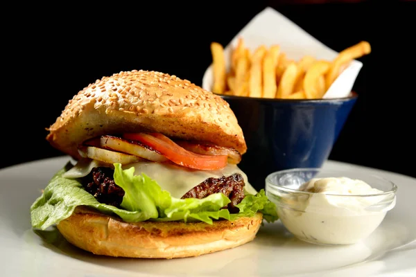 Patates kızartmalı hamburger ve siyah arkaplanda sos.