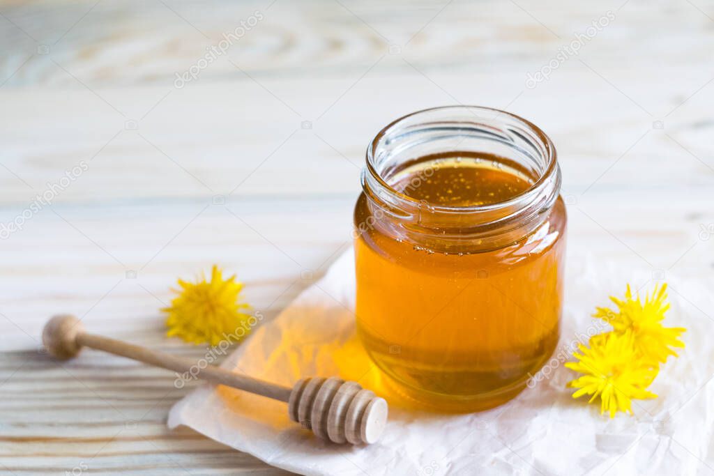 Dandelion jam, honey, syrup in a glass jar on a wooden table with fresh dandelion flowers, Medicine, healthy food, health benefits from nature. Selective focus
