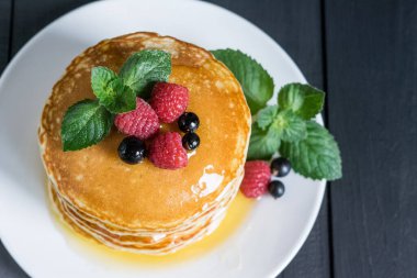 Amerikan klasik krepleri ahududulu, siyah frenk üzümlü, bal ve nane arkaplanlı, seçici odaklı..