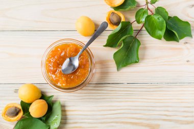 Cam kavanozda kayısı reçeli ve tahta kırsal masada olgun kayısılar seçici odak, yatay yönelim, üst görüş.