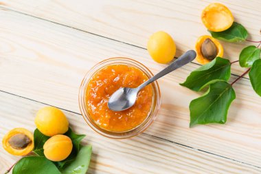 Cam kavanozda kayısı reçeli ve tahta kırsal masada olgun kayısılar seçici odak, yatay yönelim, üst görüş.