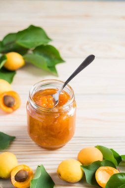 Cam kavanozda kayısı reçeli ve ahşap kırsal masada olgun kayısılar, seçici odak, dikey yönelim