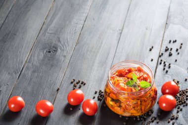 Koyu ahşap arka planda olgun domatesli cam kavanozda kurutulmuş domatesler seçici odak, kopyalama alanı