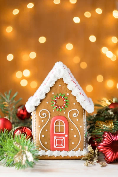 Çam dalları ve noel dekorasyonlu güzel zencefilli ev, arka planda ışıklar, dikey yönelim, seçici odaklanma