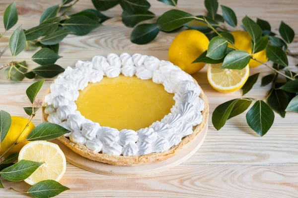 Fresh homemade lemon pie with meringue on light wooden background, selective focus