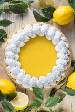 Açık ahşap arka planda kremalı taze ev yapımı limonlu tart, üst görünüm, dikey yönelim.