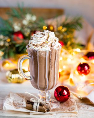 Kadehte krem şantili Noel sıcak çikolatası, şenlikli arka plan. Seçici odak.