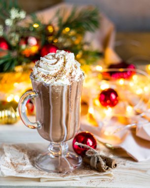 Kadehte krem şantili Noel sıcak çikolatası, şenlikli arka plan. Seçici odak.