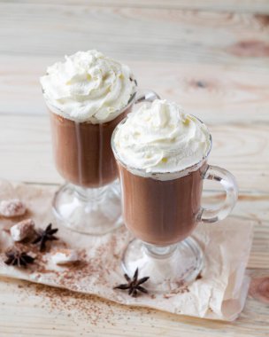 Hafif ahşap arka planda çırpılmış kremalı iki bardak kakao. Seçici odak.