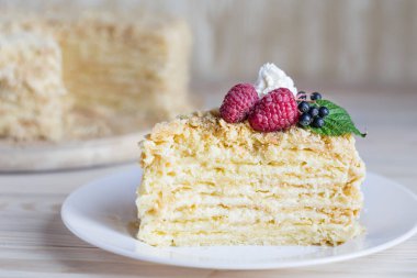 Bir parça Napolyon keki. Kremalı vanilyalı tatlı tabakta. Ahududu ile servis edilen lezzetli hamur işi. Beyaz tabakta pişmiş turta. Seçici odak