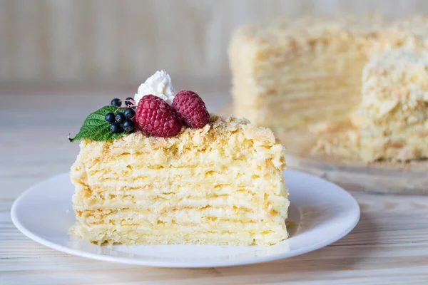 Piece of napoleon cake. Creamy vanilla slice dessert on plate. Delicious pastry served with raspberry. Layered baked pie on white plate. Selective focus