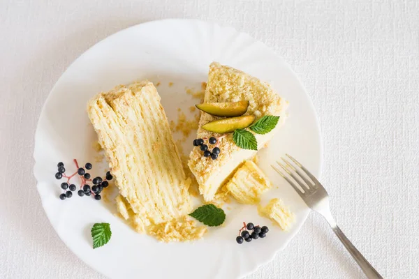 Beyaz arka planda çatalla beyaz tabakta iki dilim Napolyon pastası. Seçici odak, üst görünüm