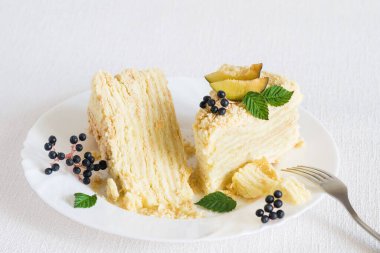 Beyaz arka planda çatalla beyaz tabakta iki dilim Napolyon pastası. Seçici odak, yakın plan