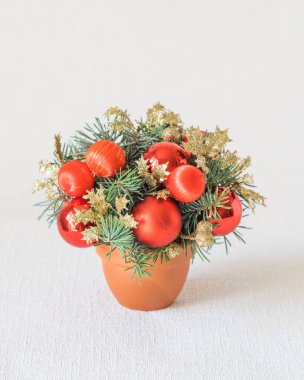 Kırmızı süslemeleri ve beyaz zemin üzerinde köknar ağacı dalları olan küçük ve güzel bir kış festivali kompozisyonu. Dikey oryantasyon, kopyalama uzayı. Noel ve yeni yıl