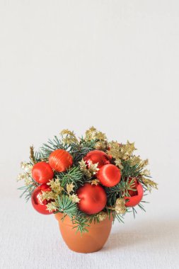 Kırmızı süslemeleri ve beyaz zemin üzerinde köknar ağacı dalları olan küçük ve güzel bir kış festivali kompozisyonu. Dikey oryantasyon, kopyalama uzayı. Noel ve yeni yıl