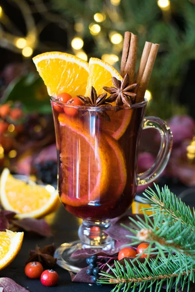 背景にクリスマスライトと黒の木製のテーブルの上にオレンジのスライスとスパイスとマルチワイン 選択的フォーカス クローズアップ — ストック写真