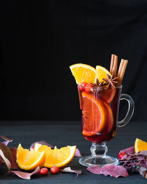 Portakal dilimli sıcak şarap ve siyah ahşap arka planda baharatlar. Seçici odak, kopyalama alanı