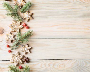 Zencefilli kurabiyeler, köknar ağacı dalları ve ahşap arka planda böğürtlenler. Noel, yeni yıl ve kış tatili konsepti. Üst görünüm, yatay yönelim, kopyalanma alanı