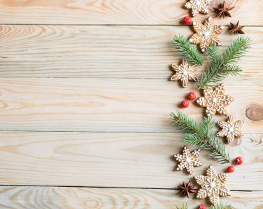 Zencefilli kurabiyeler, köknar ağacı dalları ve ahşap arka planda böğürtlenler. Noel, yeni yıl ve kış tatili konsepti. Üst görünüm, yatay yönelim, kopyalanma alanı