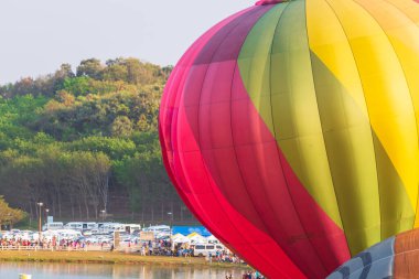 Uçan renkli sıcak hava balonunun yakın plan fotoğrafı. Arka planda orman ve araba otoparkı var. Sıcak hava balonu festivali kavramı