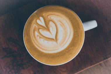 Sanatın klasik tonu sıcak cappuchino kahve fincanı ahşap masada.