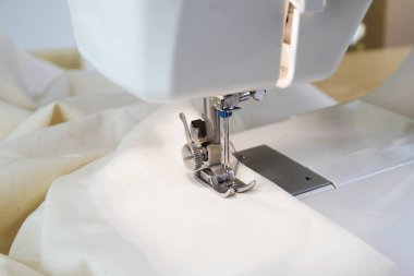 dikiş makinesi ile iğne ve ayağı, altında beyaz kumaş, seçilen odak kapatın, alan derinliği dar
