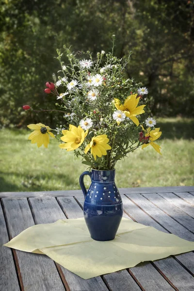 bouquet of autumn flowers in a rural vase on a rustic wooden table in the garden, vertical, selected focus