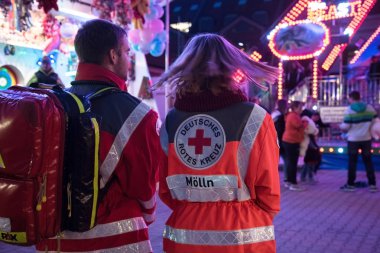 Moelln, Almanya, 1 Kasım 2018: genç adam ve kadın arkadan gece lunapark, acil ilk yardım için kurtarma sırt çantası ile Alman Kızılhaç, hareket bulanıklığı, seçilen odak