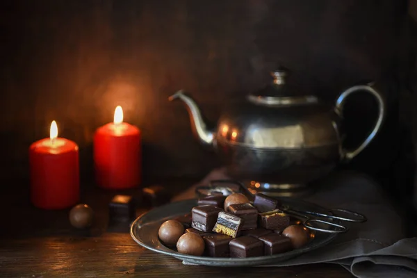 Рождественские Шоколадные Конфеты Две Красные Свечи Серебряный Чайник Деревенском Деревянном — стоковое фото