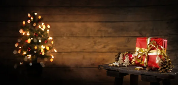 古いスツール 素朴な木製の壁 コピー スペース パノラマのフォーマット 選択したフォーカスに対して背景のライトとぼやけた木に赤いギフト ボックス クリスマス装飾 — ストック写真