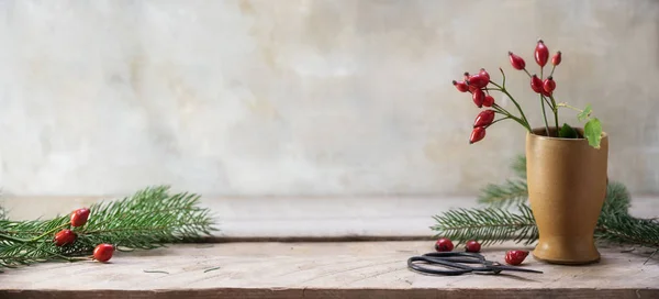 玫瑰和冷杉树枝在一个石器花瓶和乡村木桌上安排圣诞装饰 复古背景与复制空间 全景横幅格式 选择焦点 — 图库照片