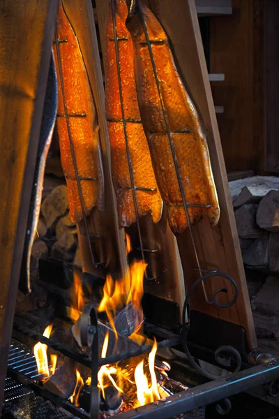 Il salmone è fumato a fuoco aperto al mercatino di Natale di Luebeck, Germania, verticale — Foto Stock