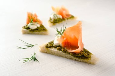 kopya alanı, seçilen odak, dar alan derinliği ile hafif bir arka plan üzerinde kanepeler somon füme, pesto, krema ve dereotu ile garnitür