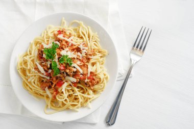 kıyma ve domates, parmesan ve maydanoz soslu spagetti garnitür beyaz bir tabloda, yukarıdan, kopya alanı yüksek açılı görünüş