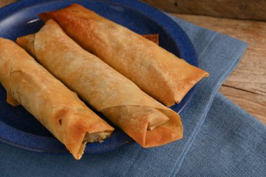 bir rustik ahşap, seçilen odak, dar alan derinliği üzerinde mavi bir plaka üzerinde dolgu baharatlı Etli dolma filo ya da yufka hamur rulo