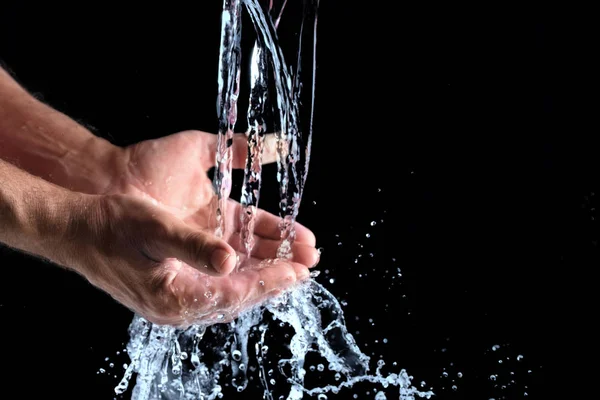 Čerstvá voda dostane do lidských rukou na černém pozadí — Stock fotografie