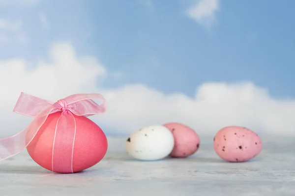 Розовые и белые пасхальные яйца, один с лентой против размытого b — стоковое фото