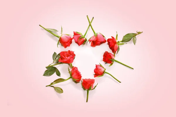 Roses rouges posées en forme de coeur sur un fond rose clair, concept d'amour avec espace de copie, vue du dessus — Photo