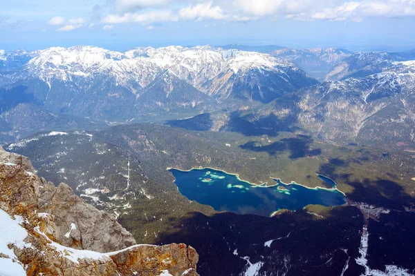 Lago Eibsee entre las montañas cubiertas de nieve cerca de Garmisch-Partenkirchen, vista aérea bajo un cielo azul con nubes, Alpes bávaros, Alemania, Austria, espacio de copia — Foto de Stock