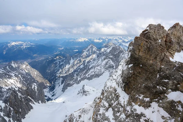 Vista en el valle desde el Zugspitze, la montaña más alta de Alemania en los Alpes bávaros cubiertos de nieve, cielo nublado, espacio de copia — Foto de Stock