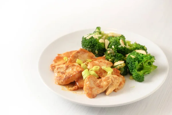 Mariniertes Hähnchenbrustfilet mit Frühlingszwiebeln und Brokkoli mit Mandelstäbchen als gesunde Mahlzeit mit wenig Kohlenhydraten zum Abnehmen auf einem Teller, Hintergrund verschmilzt mit Weiß, Kopierraum — Stockfoto