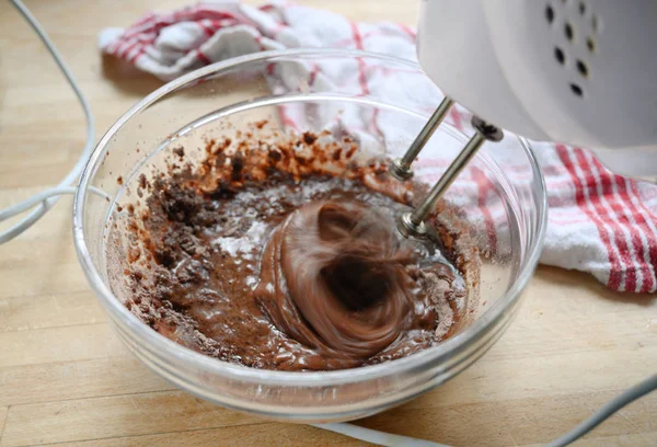 Mezclador eléctrico en acción revolviendo masa para pastel de chocolate en un tazón de vidrio, desenfoque de movimiento, concepto de cocción — Foto de Stock