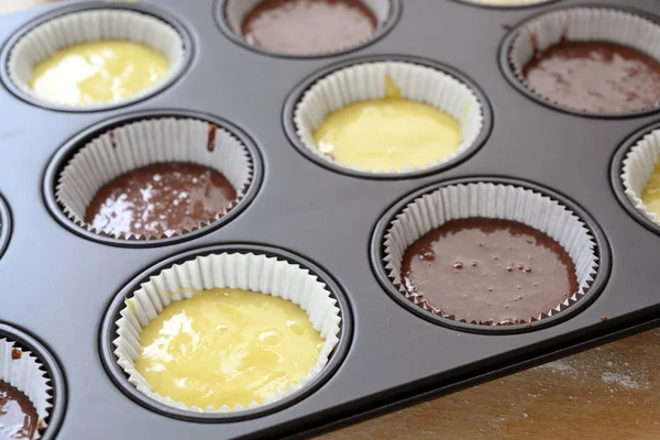 Поднос для выпечки кексов, наполненный двумя видами теста для торта, легкие и шоколадные для вкусных кексов, выбранный фокус — стоковое фото