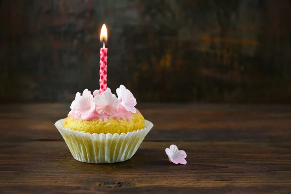 복사 공간이있는 소박한 갈색 배경에 어두운 나무 판에 분홍색 장식과 불타는 촛불이있는 머핀 또는 컵 케이크 — 스톡 사진