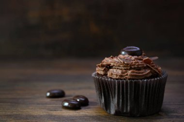 kakao yağı krema, çikolata cipsi ve rustik ahşap kahve çekirdekleri ile kahverengi cupcake, kopya alanı