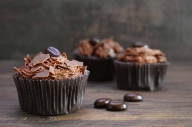 kakao yağı krema, çikolata cipsi ve rustik ahşap kahve çekirdekleri ile kahverengi cupcakes, kopya alanı