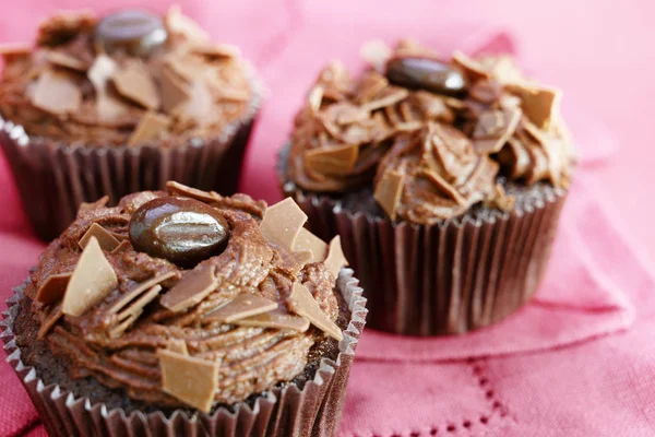 Cupcakes marrones con crema de manteca de cacao y chispas de chocolate en un mantel rosa, primer plano — Foto de Stock