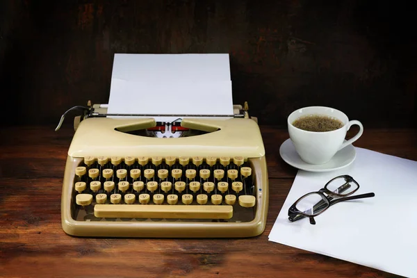 Starý psací stroj z padesátníků s papírem, kávou a sklenicemi na tmavém dřevěném stole — Stock fotografie